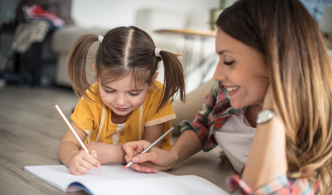 Mom and daughter drawing in a notebook together